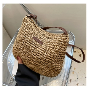 Detail shot of the woven straw bag featuring a brown leather strap and decorative patch