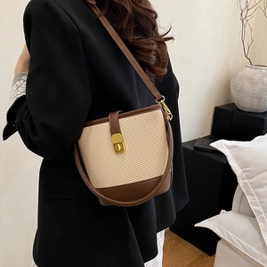 Minimalist beige woven bucket bag with brown leather trim and gold twist lock clasp