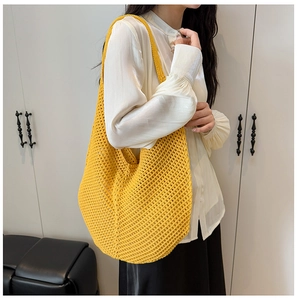 Detail of a large yellow hand-woven hobo bag with a hollow crochet texture and wide strap