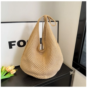 Close-up of beige crochet hobo bag with hollow knit texture on a wooden desk