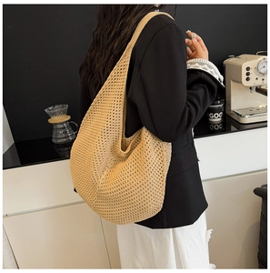 Detail of a large beige hand-woven hollow mesh shoulder bag with a bohemian hobo style