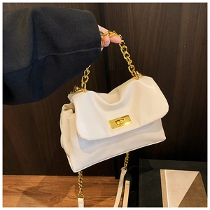 Detalle del bolso plisado crema con cadena dorada y elegante hebilla metalizada