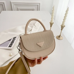 Nahaufnahme beige Satteltasche mit gewebter Textur und dekorativem Dreiecksverschluss