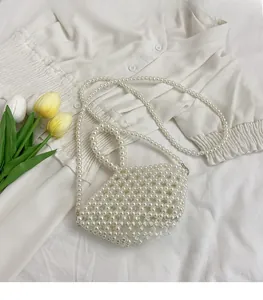 Detail of white handmade pearl beaded handbag with strap on elegant white fabric
