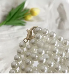 Detail of multi-layer white pearl handbag with high-quality gold hardware clasp