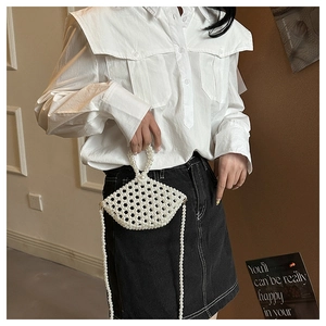 Detail of white handmade pearl beaded handbag with circular handle and long crossbody chain