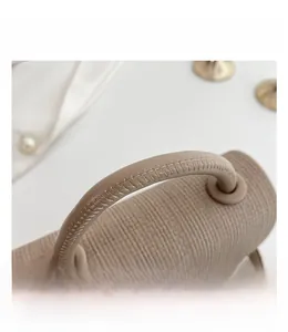 Detail des gesteppten Tragegriffs an einer beigen gestreiften Box-Tasche