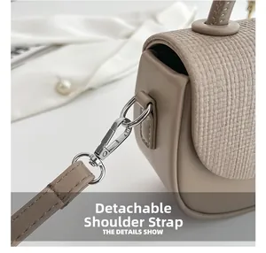Detail eines abnehmbaren Schultergurts mit Metallkarabiner an einer beigen Box-Tasche
