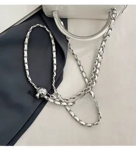 Detail of silver chain strap with leather weave and quilted ball slider on cream box bag