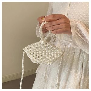 Detail of handmade pearl beaded crossbody bag with elegant handle on model outfit