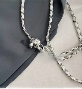 Macro detail of silver-tone chain strap with white leather and adjustable metal ball buckle