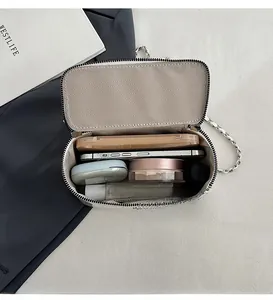 Detail view of the spacious inner compartment of the white chain bag with daily items