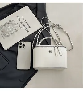 Close-up of white glossy crossbody bag with silver camellia logo and metal handle