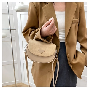 Details einer beigen Leder- und Web-Umhängetasche getragen zu einem braunen Blazer