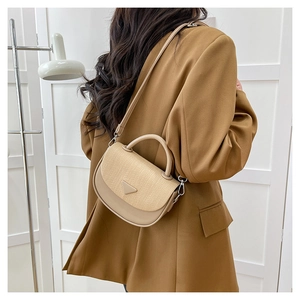Detail der minimalistischen zweifarbigen Umhängetasche mit gewebter Klappe auf beige Leder