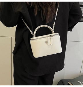 Detail of white mini box bag with chain strap and flower metal logo on leather