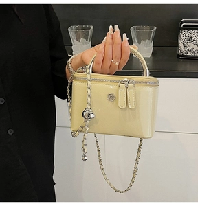 Close-up of pale yellow patent leather box bag with silver flower hardware and chain strap