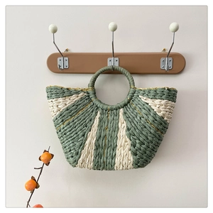 Dettaglio borsa in paglia intrecciata a righe verde salvia e beige con manici tondi