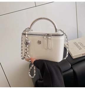 Detail of white patent leather box bag with silver camellia buckle and chain strap