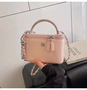 Detailed shot of pink patent leather handbag featuring silver flower and metal handle
