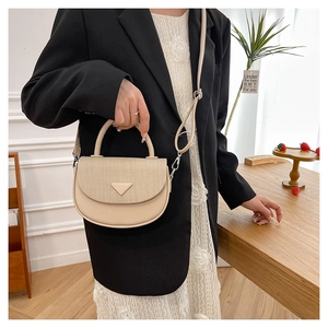 Detail einer cremefarbenen Satteltasche mit geflochtener Klappe und Dreiecksakzent am Model