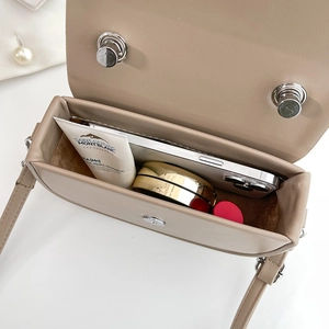 Draufsicht auf kompakte Umhängetasche zeigt Innenraum mit Handy und Make-up-Essentials