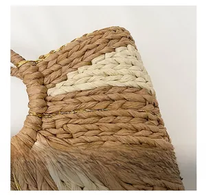 Dettaglio della trama in paglia con cuciture dorate e design patchwork beige della borsa