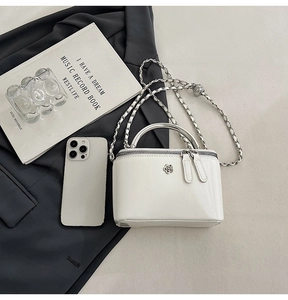 Detailed macro view of white mini box bag with silver flower badge and chain strap