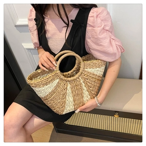 Dettaglio di una borsa a mano in paglia a mezzaluna con trama a righe e manici rotondi