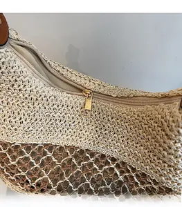 Detailansicht des goldfarbenen Metallreißverschlusses an einer zweifarbigen Strohtasche