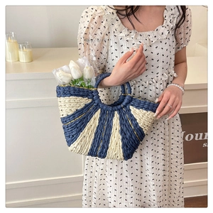 Dettaglio della borsa in paglia intrecciata blu navy e beige con manico circolare
