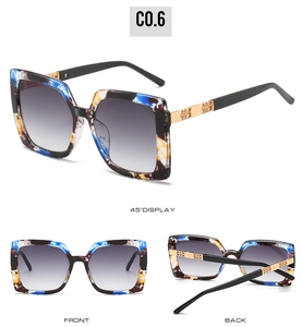 Detailansicht der quadratischen Sonnenbrille mit buntem Farbmuster und Goldketten-Element