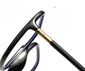Detail of square glasses showing black glossy frame and gold metal hinge connector