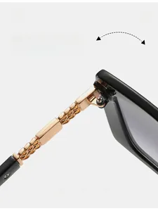Detailansicht der goldfarbenen Metallkette am Scharnier der quadratischen Sonnenbrille