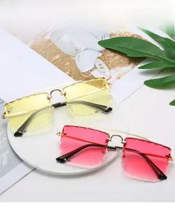 Detail of rimless square sunglasses with scalloped lens edges and gold metal temples