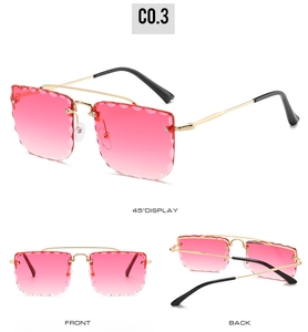 Detail view of rimless gradient pink sunglasses with wavy lens edges and gold metal frame