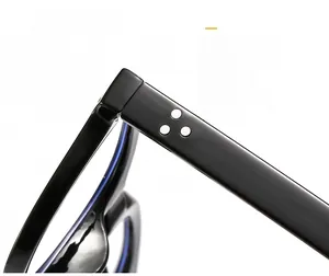 Gros plan d'une monture de lunettes noire brillante avec trois rivets argentés sur la branche
