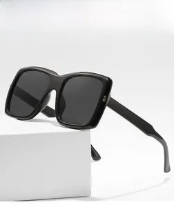 Détail de lunettes de soleil carrées avec branches noires brillantes et logo métallique doré