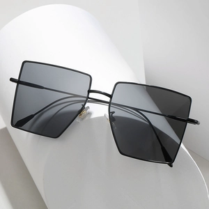 Modern minimalist square metal frame sunglasses with dark lenses on geometric white pedestals