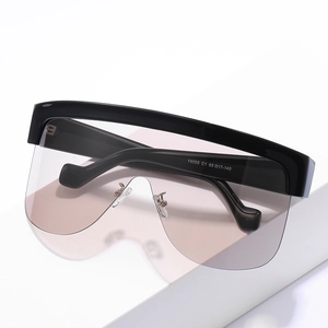Oversized wrap-around sunglasses with light pink lenses and black frame on stone
