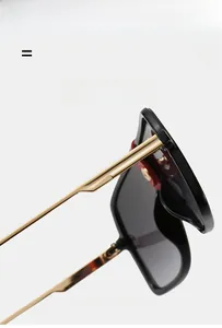 Detail of black gradient sunglasses featuring luxury gold metal temples and red accents