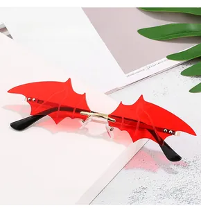 Detailed close-up of bat-wing shaped sunglasses with red lenses and gold metal bridge