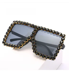 Detailed close-up of large square sunglasses featuring black rhinestones on a gold frame