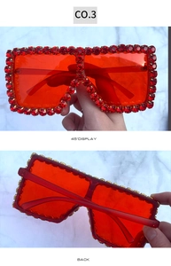 Detail view of large square red sunglasses with sparkling rhinestones on semi-transparent frames