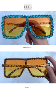 Detail view of tortoiseshell oversized sunglasses with blue rhinestones and amber lenses