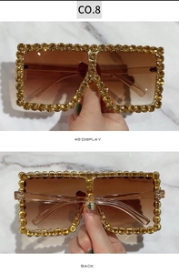 Detail of oversized square sunglasses featuring hand-set amber rhinestones and gold frame