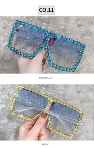 Detail view of oversized square sunglasses featuring rhinestone-encrusted frames and clear legs