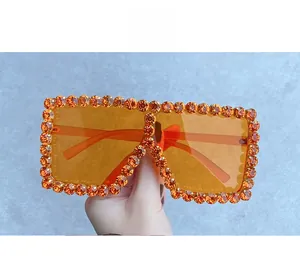 Detailed close-up of oversized square sunglasses with orange rhinestones and gradient lenses
