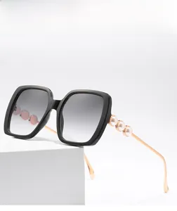 Detail of square black sunglasses featuring rhinestone-studded temples and pearl accents