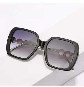 Detail of oversized square sunglasses with purple gradient lenses and pearl chain temples
